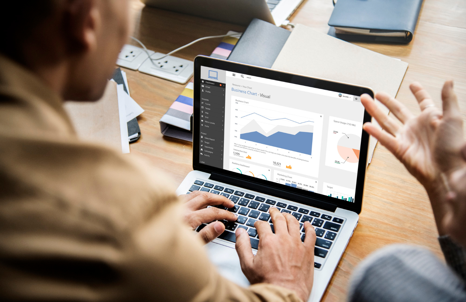 Two people discuss data and charts displayed on a laptop in a bright, modern office setting.